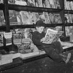 A kid reads a comic book at this newsstand in March 1942, while a few pulps are on display behind him. A kid reads a comic book at this newsstand in March 1942, while a few pulps are on display behind him.