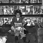 A young girl in Pittsburgh, Pa., reads a comic book, while pulps from March 1947 await sale on a rack nearby. A young girl in Pittsburgh, Pa., reads a comic book, while pulps from March 1947 await sale on a rack nearby.