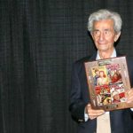 Pulpcon guest of honor Ernest Chiriacka holds a plaque, with samples of his cover art, given to him following a slideshow and a questions-and-answer session Friday night.