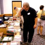 Randy Vanderbeek and others browse the tables displaying items for Saturday night’s Pulpcon auction.